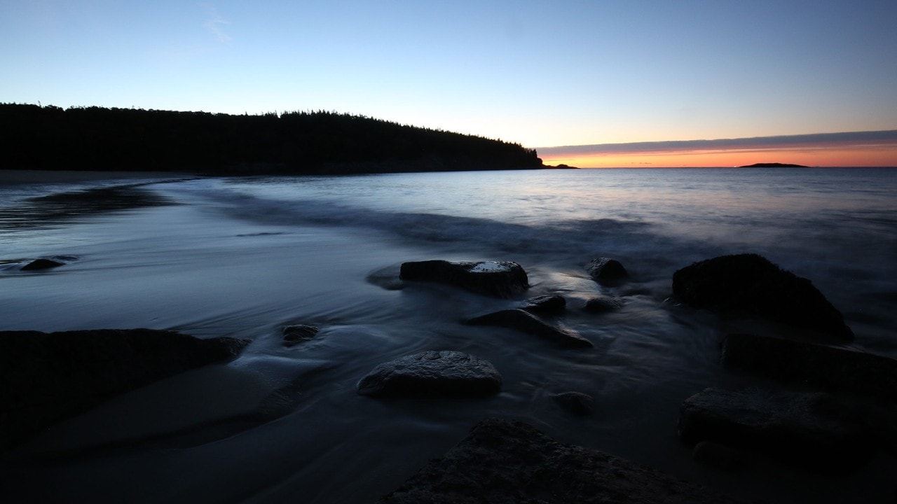 The sun rises on Sand Beach in Acadia National Park.