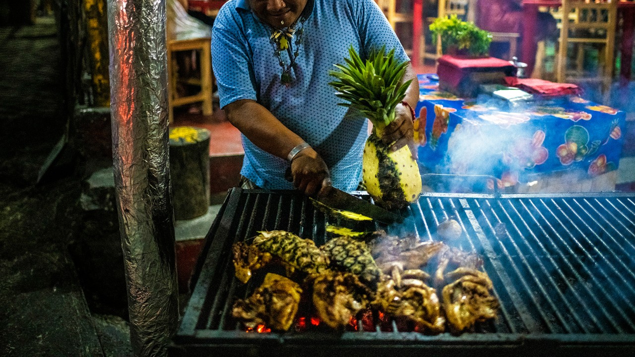 A chef grills chicken and pineapple at Pollos Los Pajaros in Pisté in Yucatán.