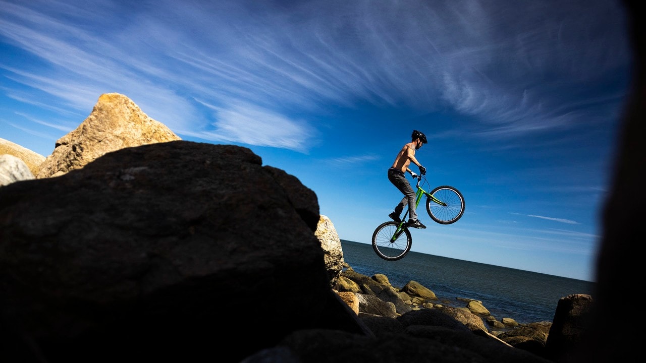 A rider hops from rock to rock on a trials bike at Hammonasset Beach State Park.