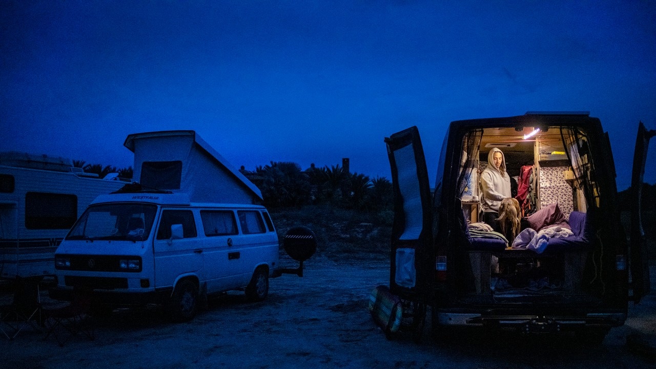Surfer Mark Kosobucki pets his dog, Trunks, in his van, which he parked on the beach.