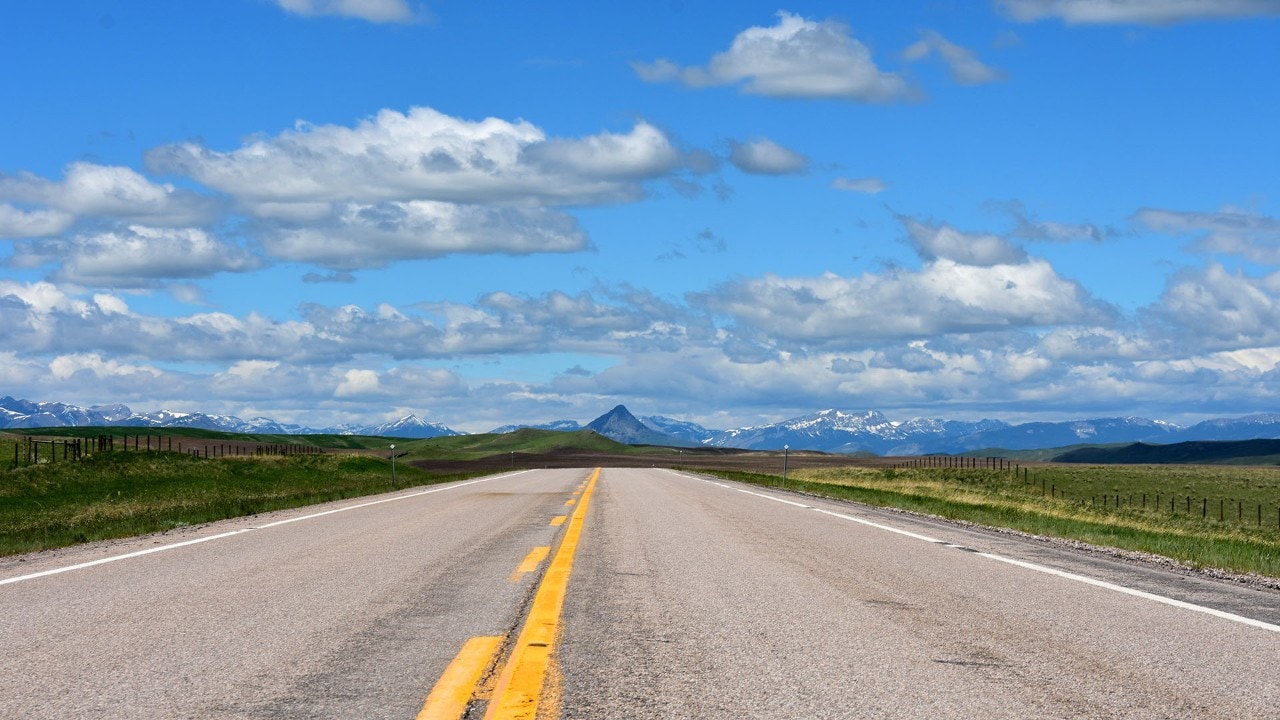 The Rocky Mountains appear in the distance after miles of open road in Montana.