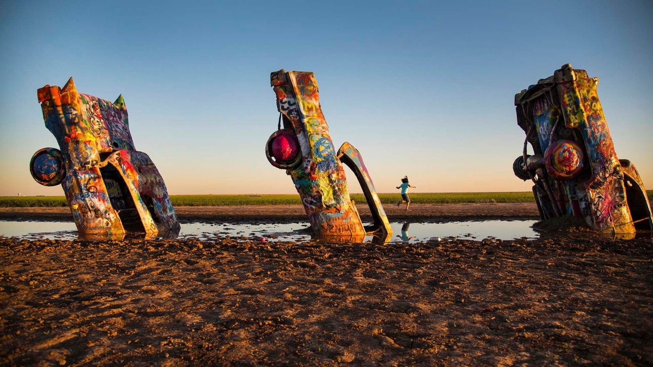 The Cadillac Ranch near Amarillo features 10 half-buried Cadillacs, where children dance in the fading Texas daylight.