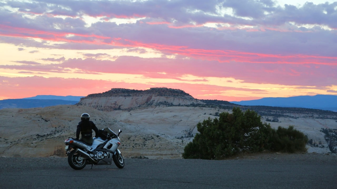 A motorcycle rider stops to enjoy sunset on "The Hogback" road.