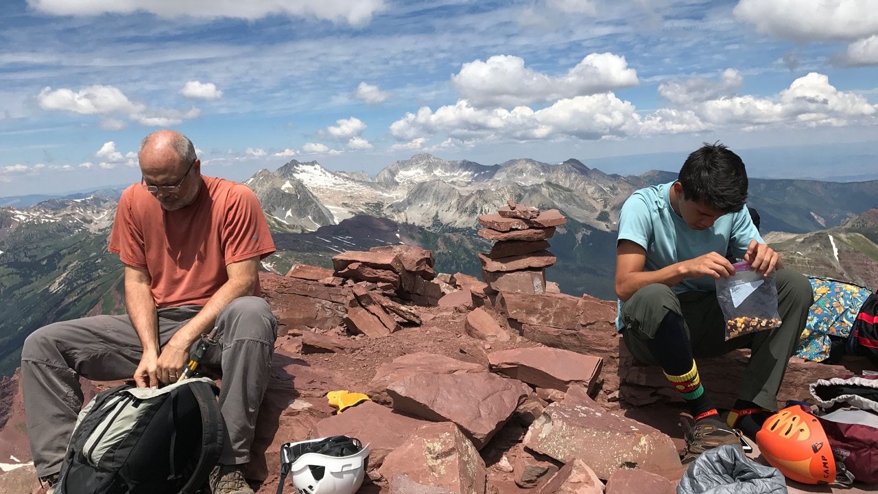 Scott and Daniel Otteman refuel atop North Maroon Peak with panoramic views of Snowmass Mountain. Photo by Shawn Otteman