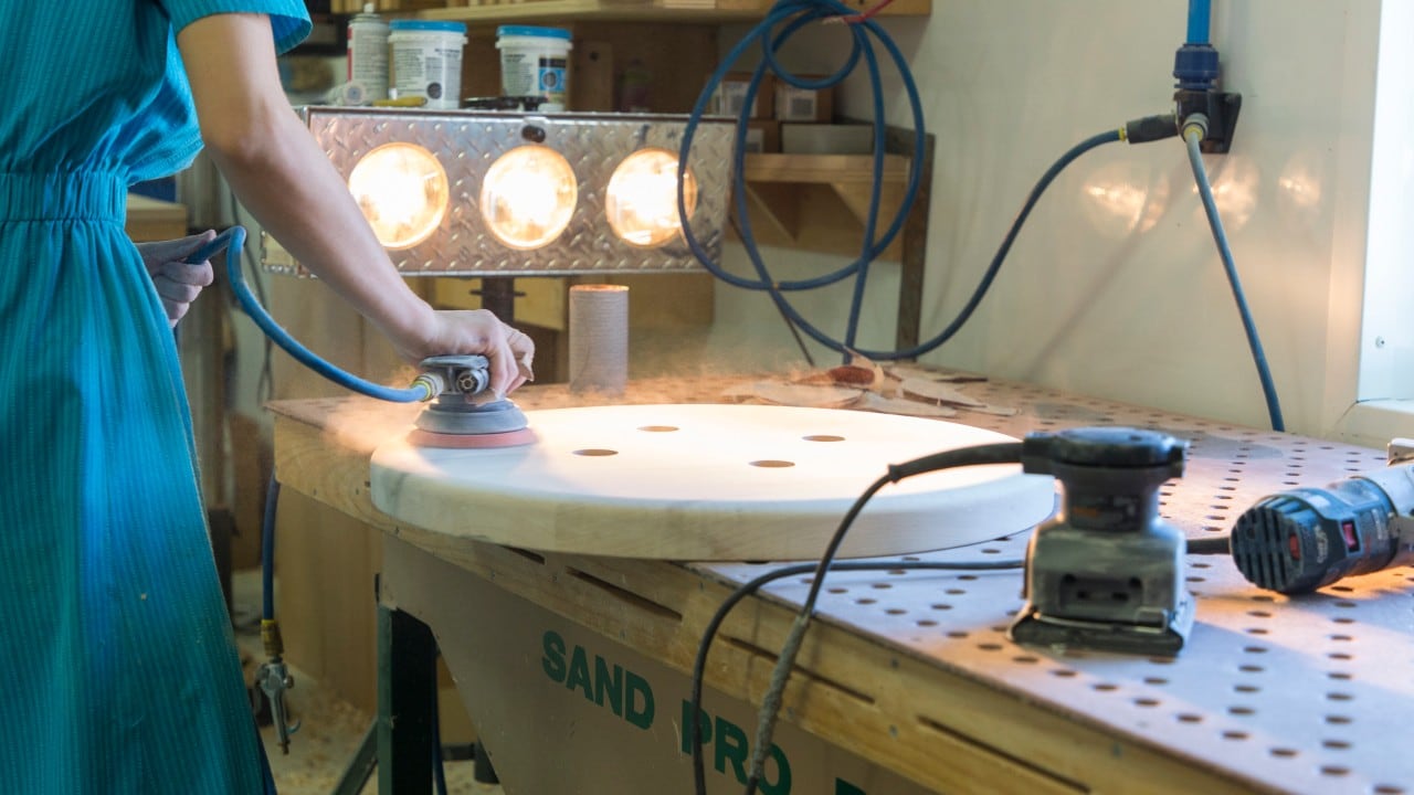 Sanding a table at West Point Woodworking