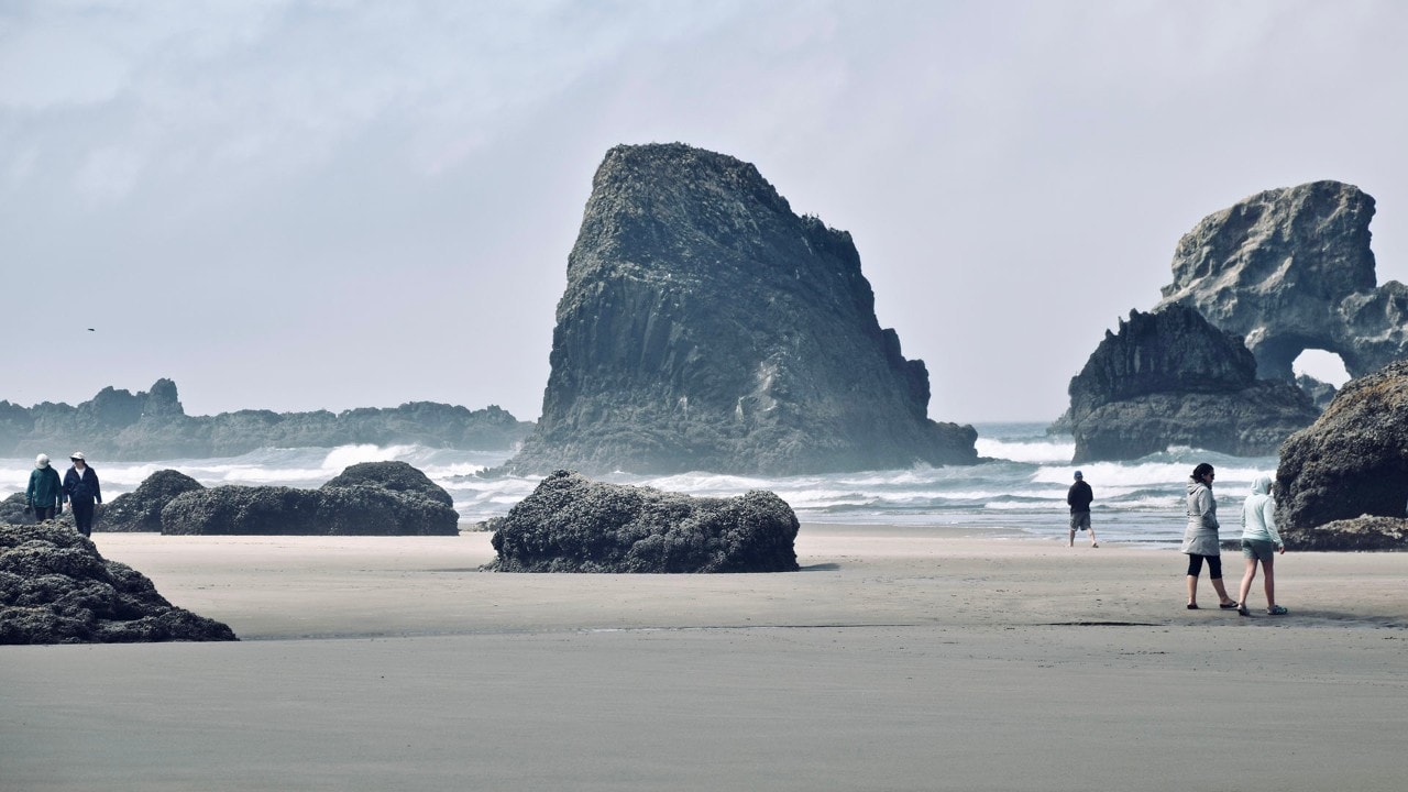 Visitors stroll among the rock formations on Crescent Beach in Ecola State Park.