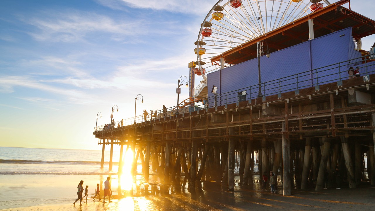 At the Santa Monica Pier, light bounces through the wooden structure at sunset.