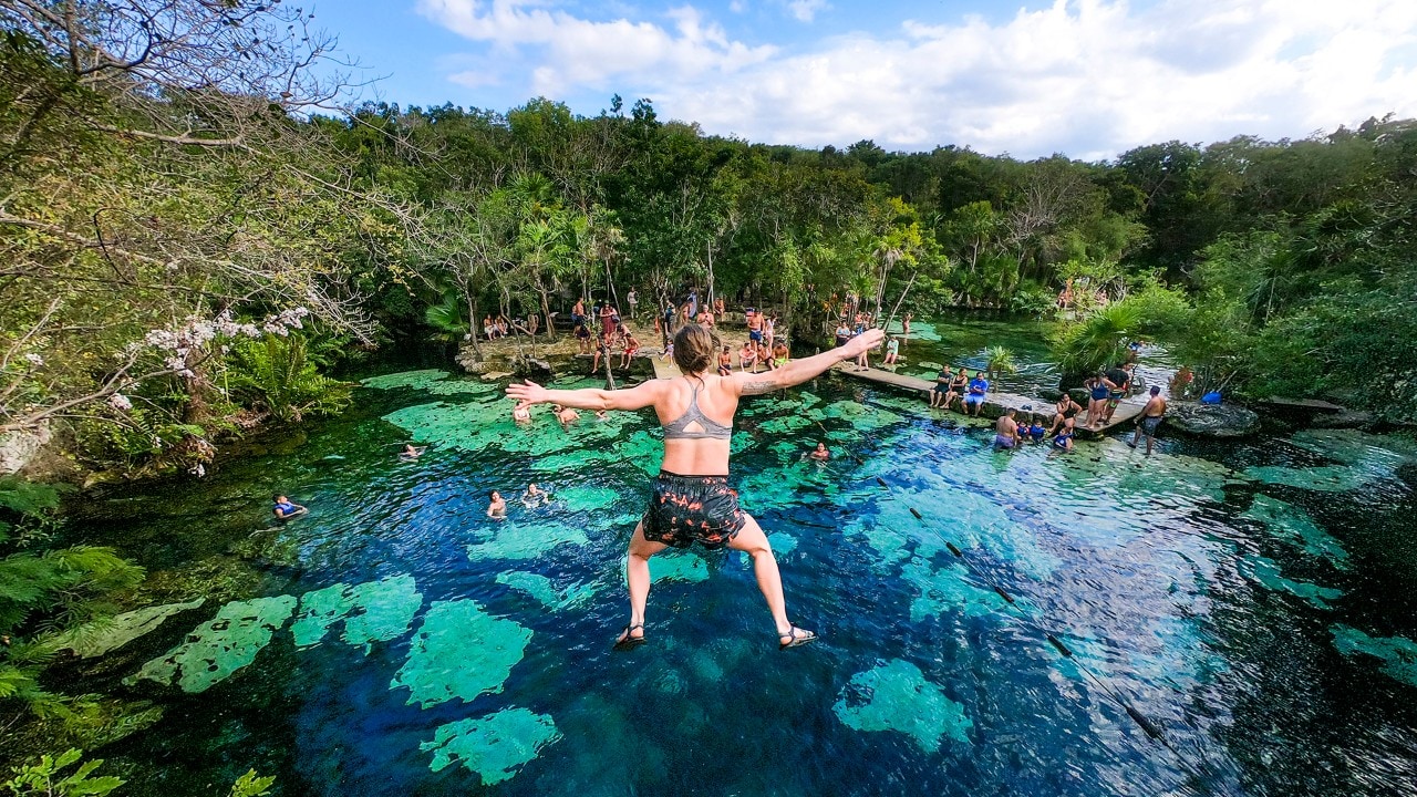 Corey leaps off a cliff into the clear waters of Cenote Azul, 30 minutes from Playa del Carmen.