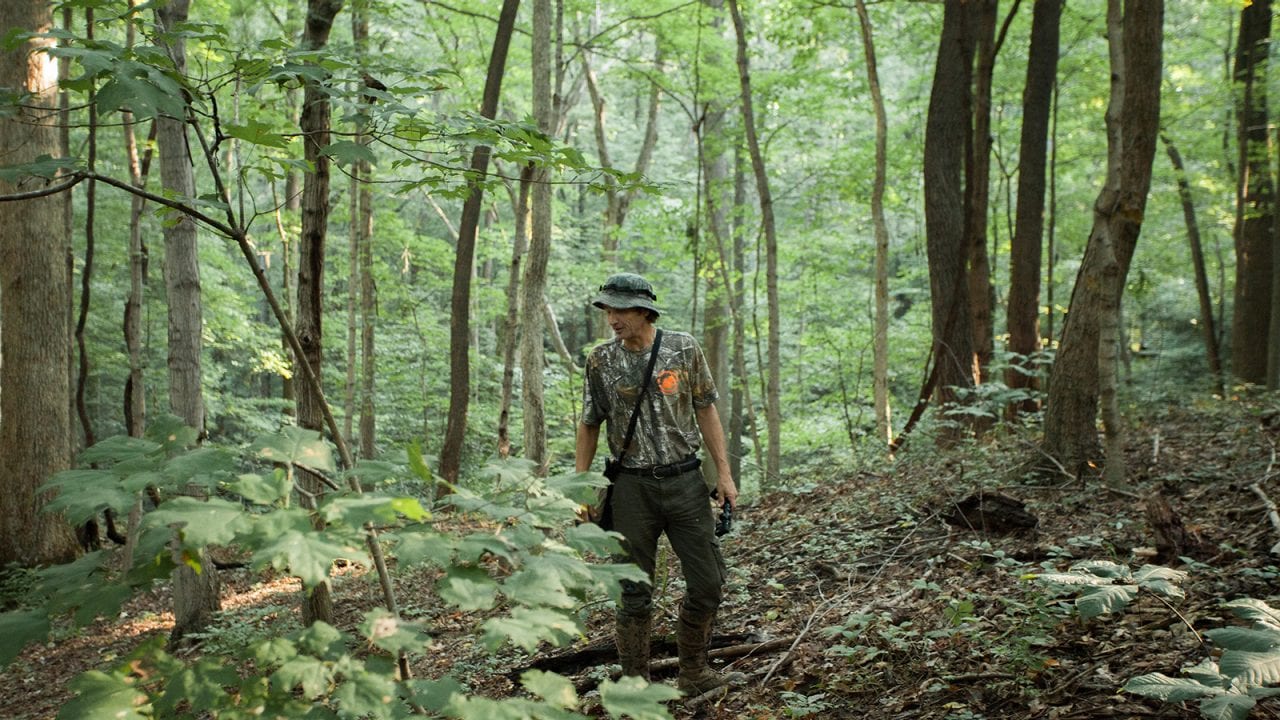 Hazlett walks through the woods. He’s well-prepared for the terrain with tough boots and pants.