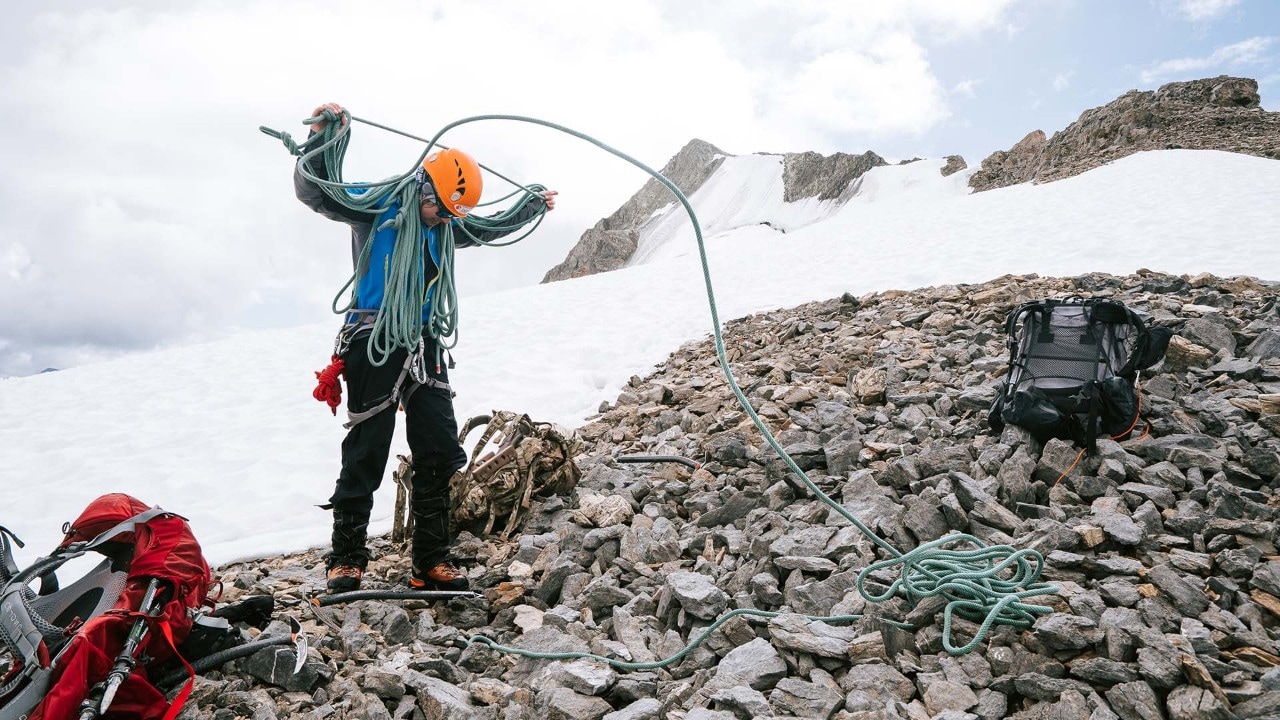 Caro, a mountaineering student, coils rope before storing it in her backpack.