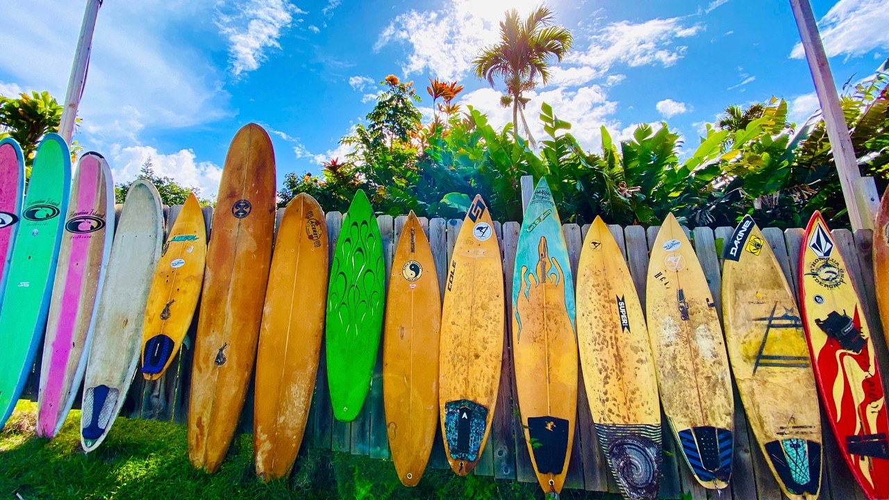 Used surfboards line a fence near Peahi.
