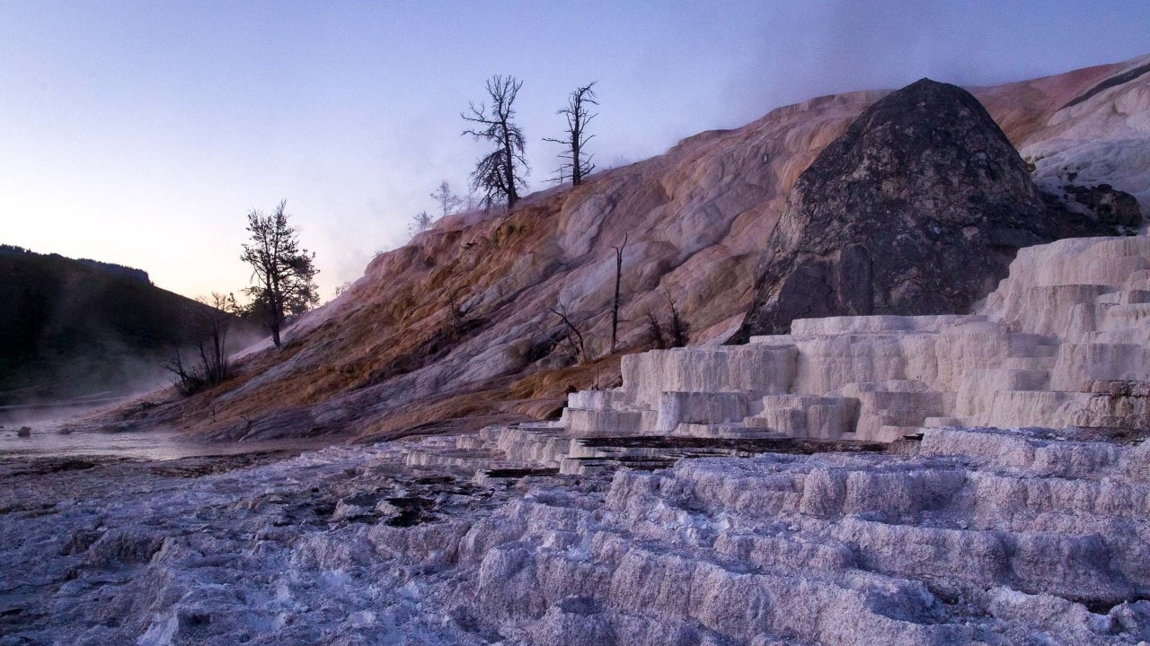 Steam rises from Mammoth Hot Springs in Yellowstone National Park, Wyoming, at dawn. The water temperature is about 170 degrees F. 