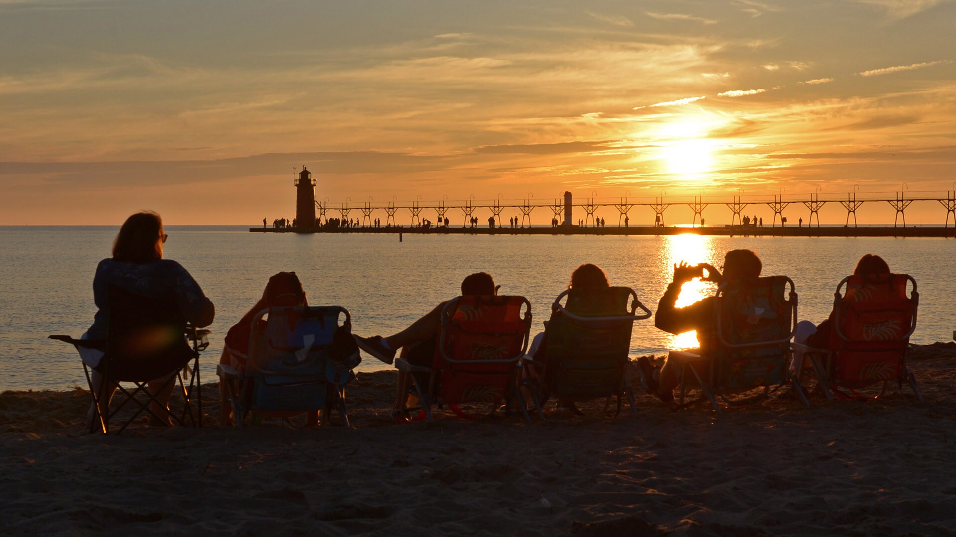 People watch the sun set near the historic lighthouse in South Haven, Michigan.