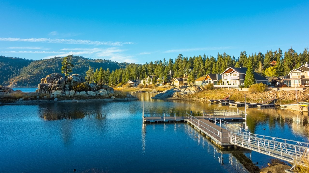 Reflections in the waters of Big Bear Lake at Boulder Bay fill the foreground leading back to vacations houses and the mountain ridges beyond, Southern California