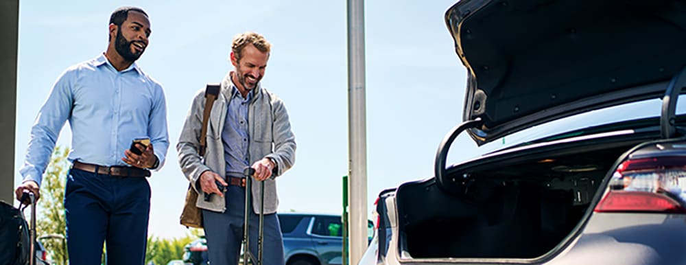 Two people walking to car with open trunk