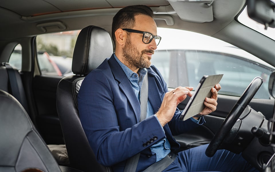 Adult businessman sit in the car and use digital tablet before go