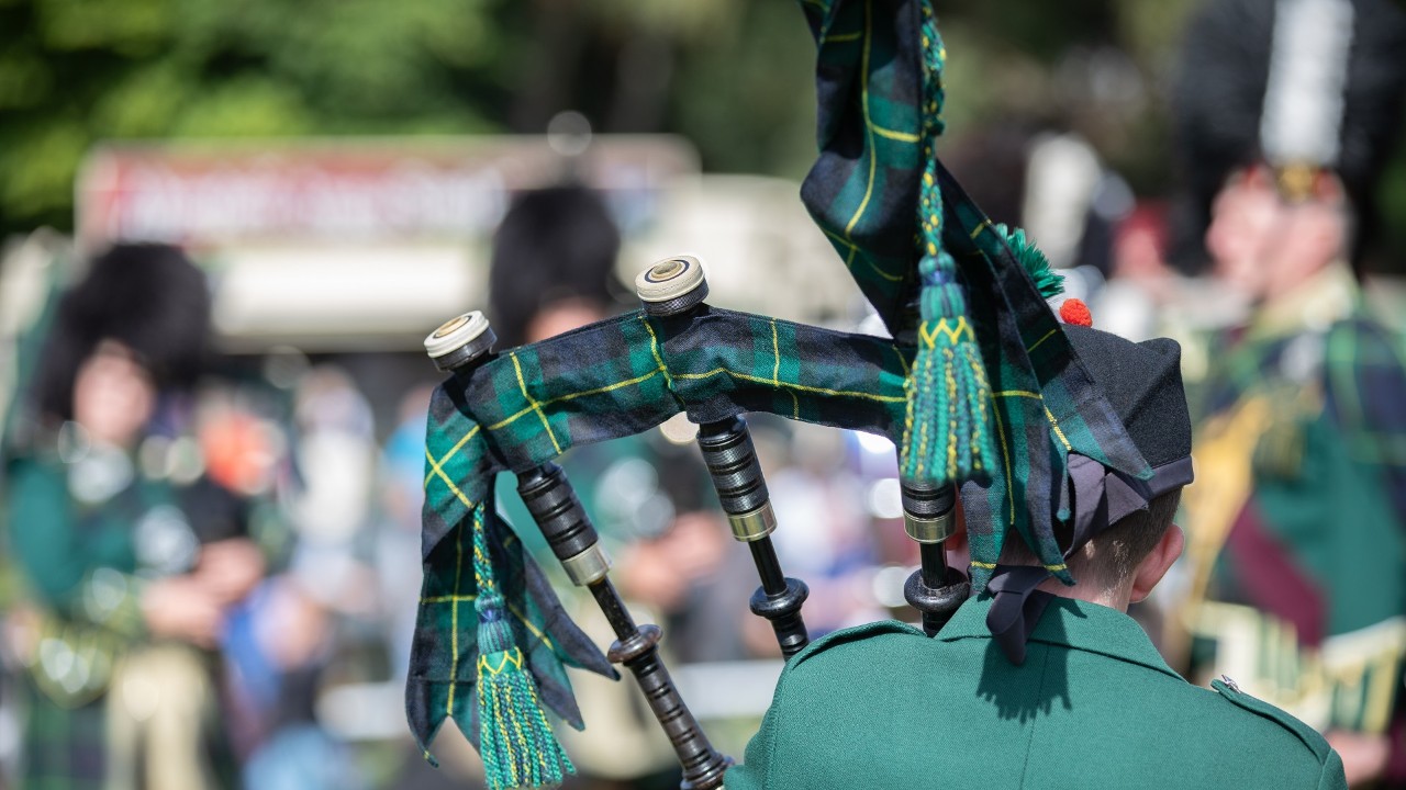 Scottish festival with the back of a bag piper playing with a larger band - Scotch Pipers.