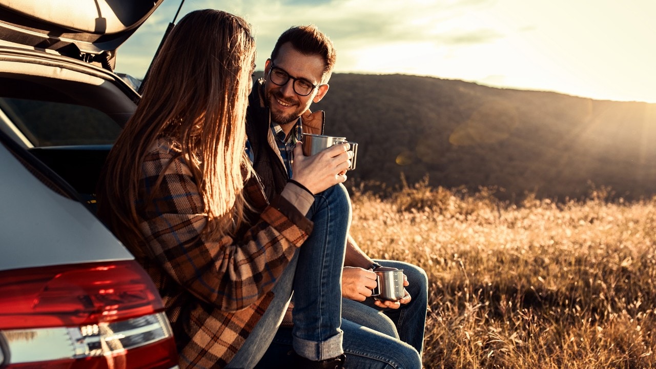Couple on road trip sitting in trunk of a car resting and drinking coffee.; Shutterstock ID 2130825881; purchase_order: Enterprise - Digital; job: ; client: ; other: 