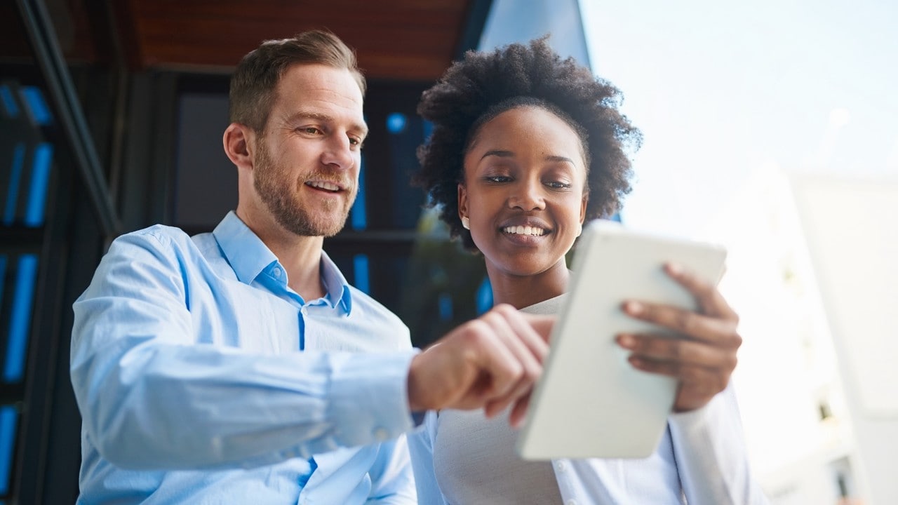 Cropped shot of two coworkers using a digital tablet while standing on a balcony