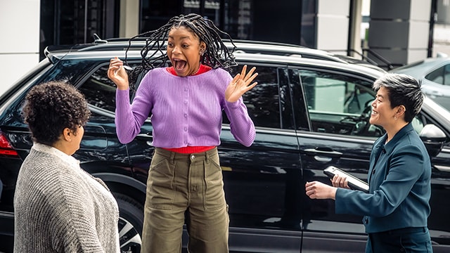 Woman jumping in excitement in front of two other people.