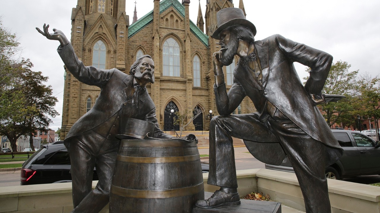 Statues of two men — both named John Hamilton Gray — talk about the confederation of Canada in front of St. Dunstan's Basilica.