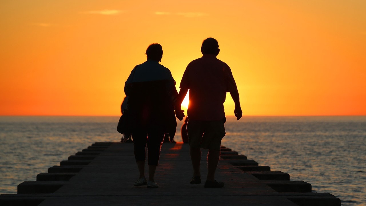 A couple walks toward the sunset. Photo by Charles Williams