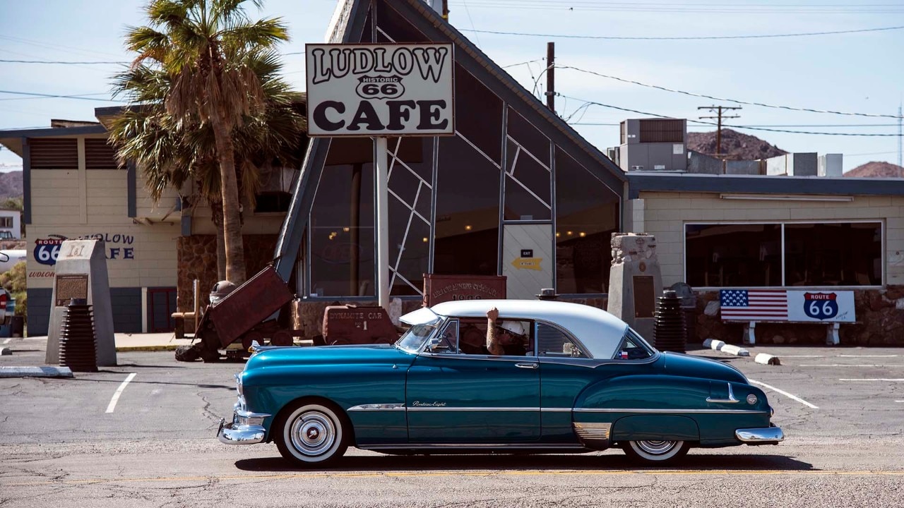 Car enthusiasts cruise by Ludlow Cafe in Ludlow, California, where I-40 and old Route 66 meet