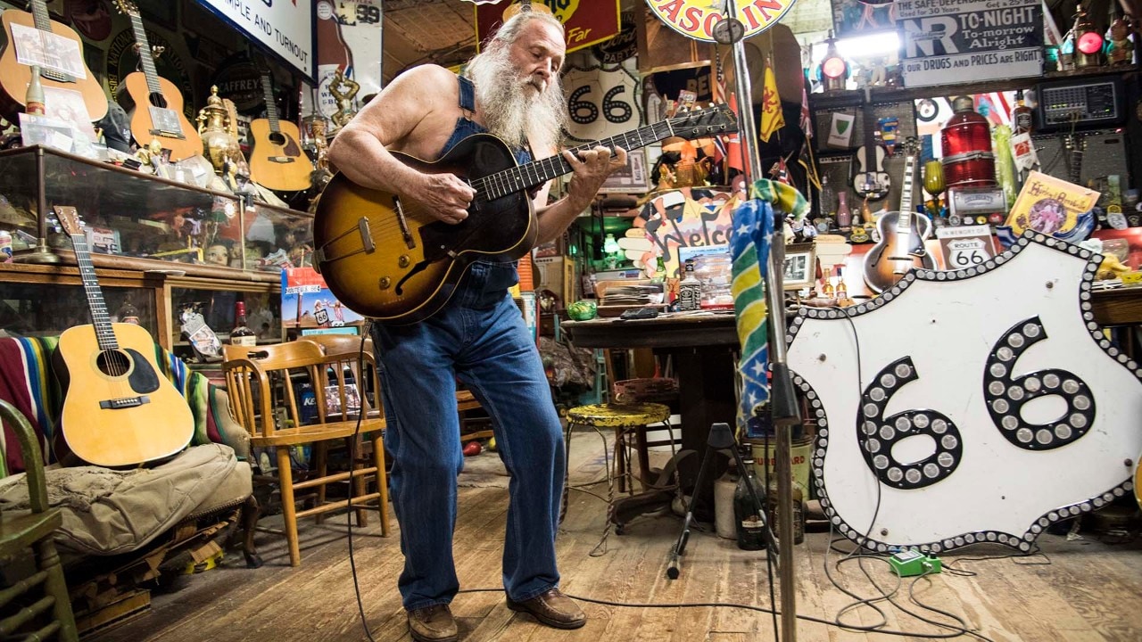 Harly Russell, the one-of-a-kind owner of the Sandhills Curiosity Shop in Erick, Oklahoma, plays guitar for visitors.