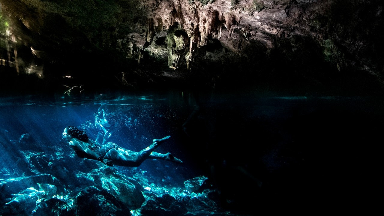 Writer Kassondra Cloos dives through the crystal-clear water at Cenote Dos Ojos.