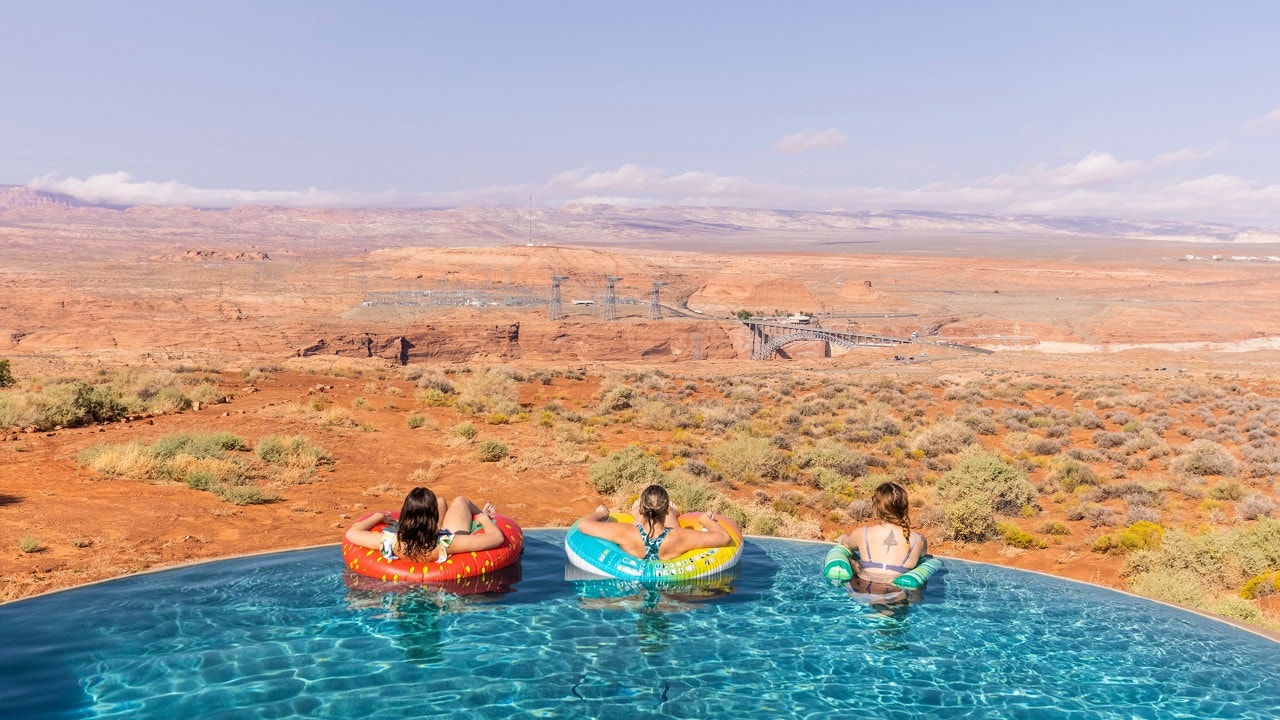From left, Sarah, Susan and Anna look at Glen Canyon Dam as they relax in the infinity pool at the rental house in Page, Arizona.