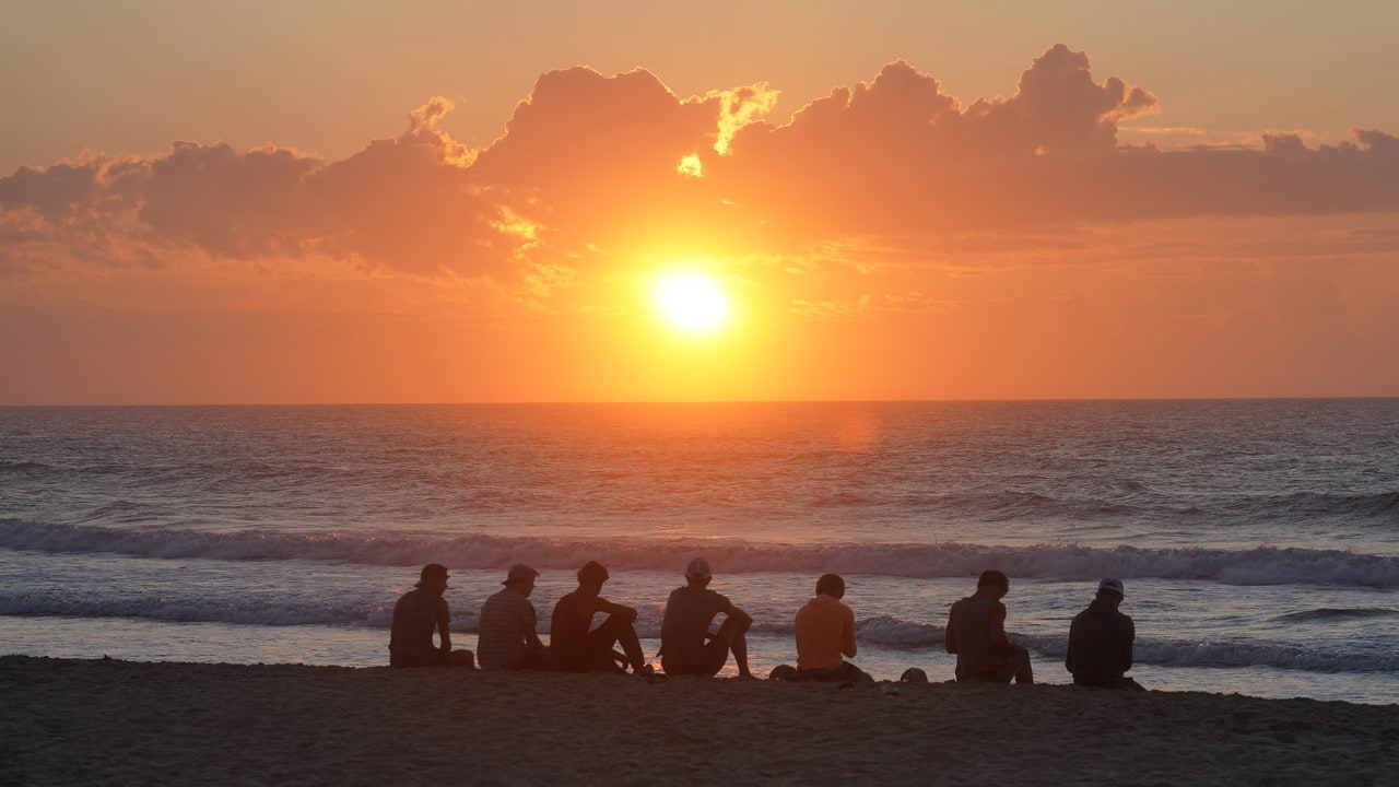 A group of young men watch the sunrise at Assateague Beach in Virginia.