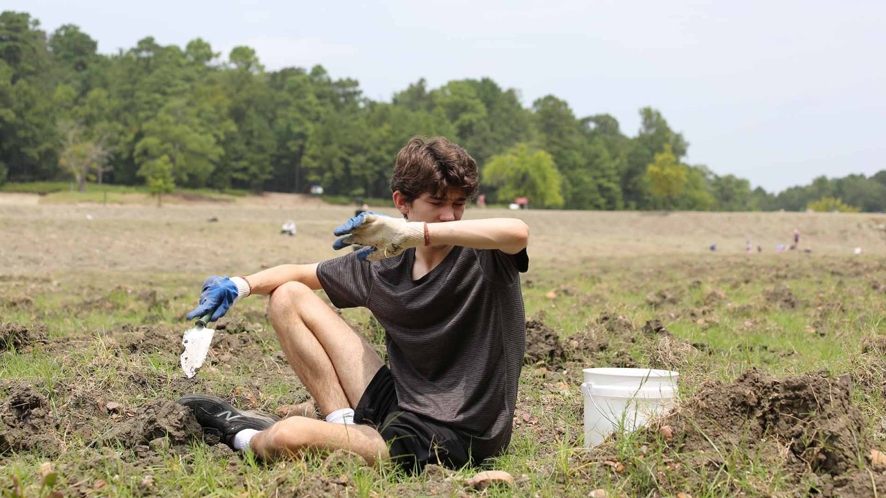 Elliot Williams wipes sweat from his forehead while digging.