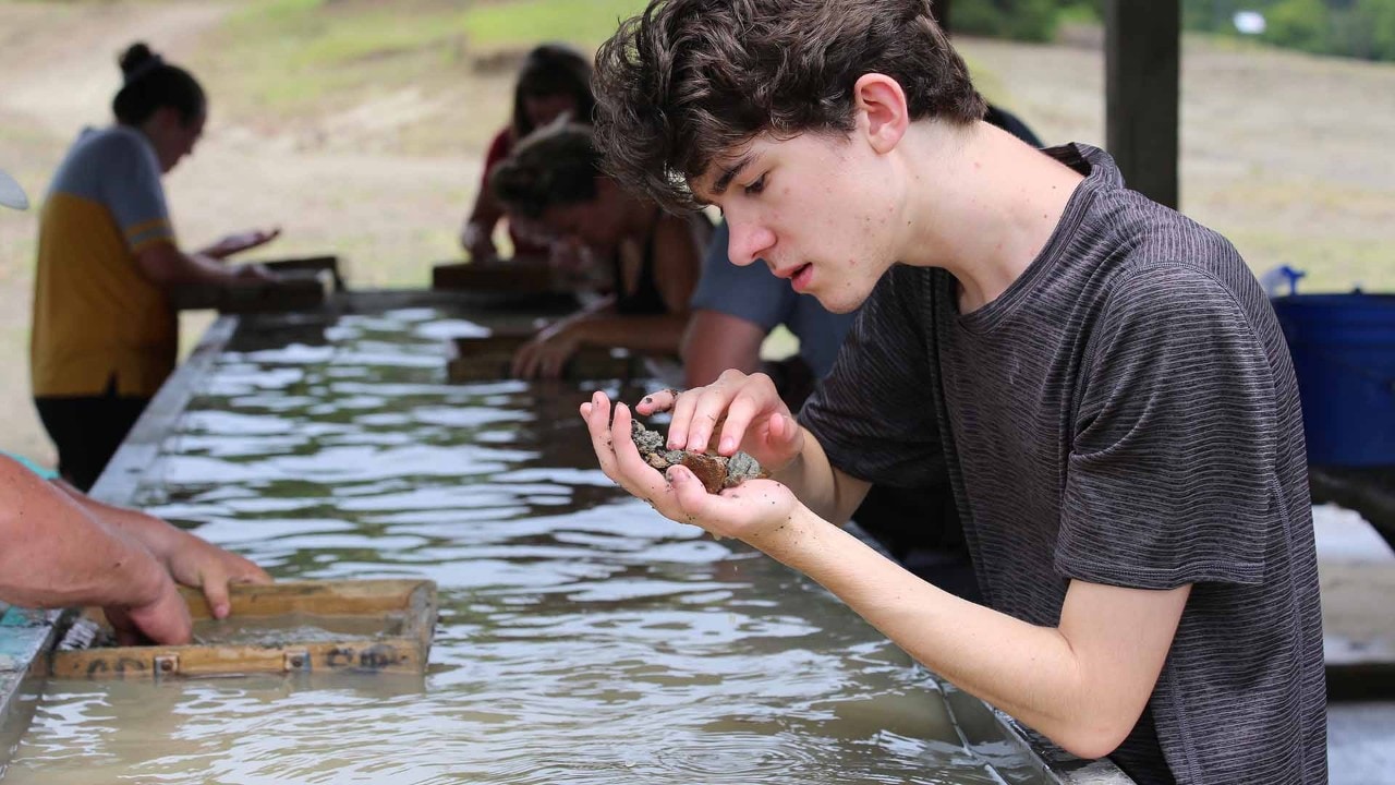 Elliot Williams carefully examines rocks that he found — no luck.