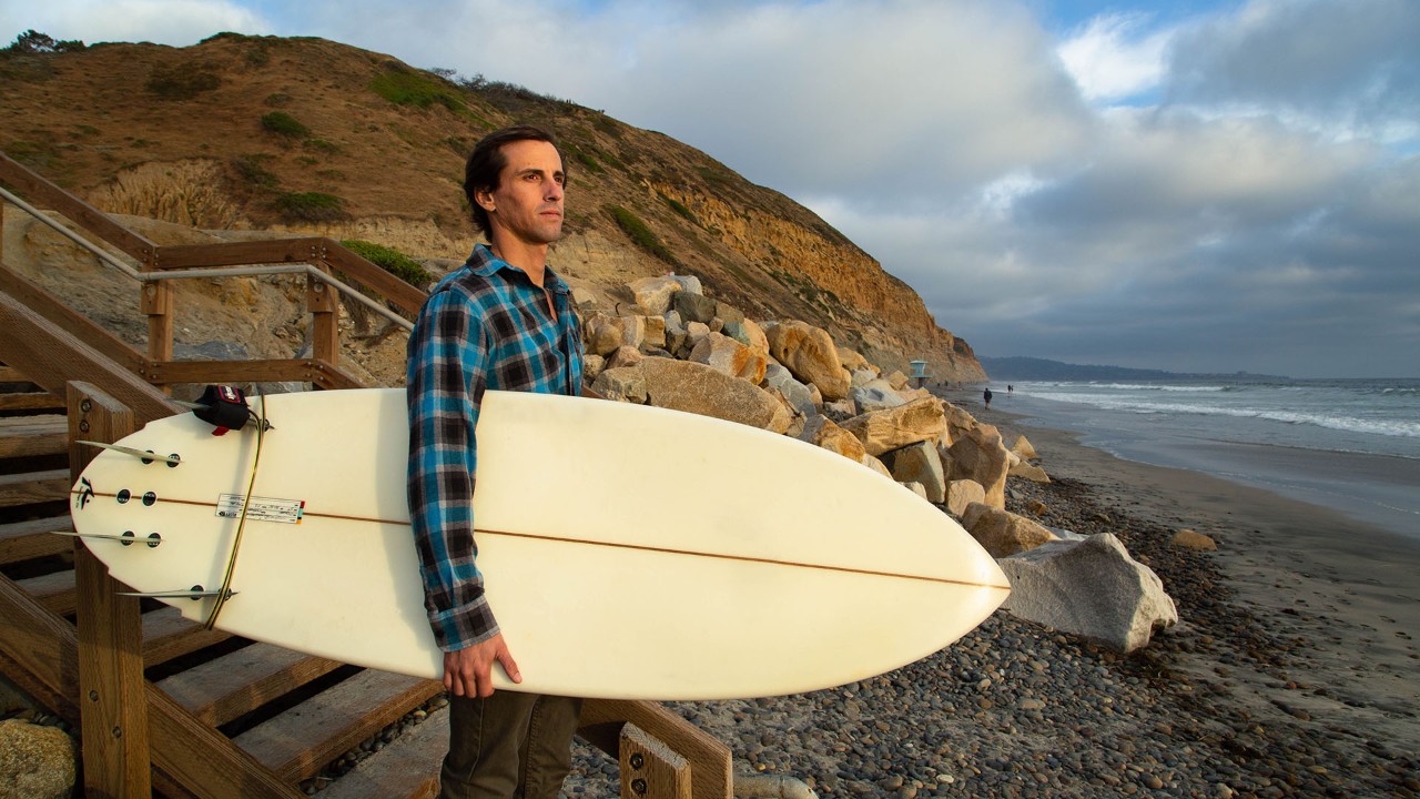 Surfer Jarrett Goldsmith heads for the ocean after the sun breaks through the clouds.