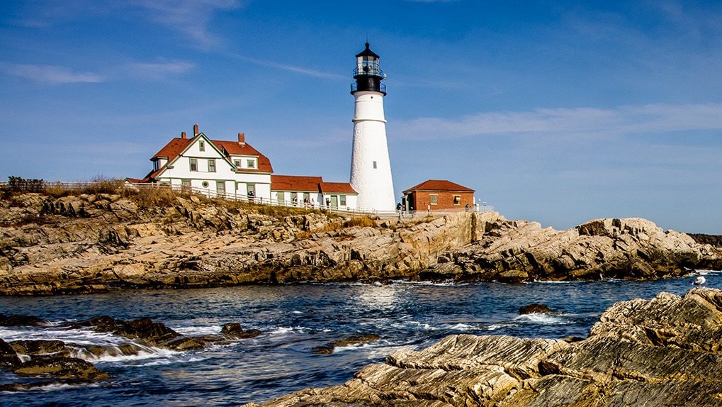 Waves crash on the rocks next to the Portland Head Light.