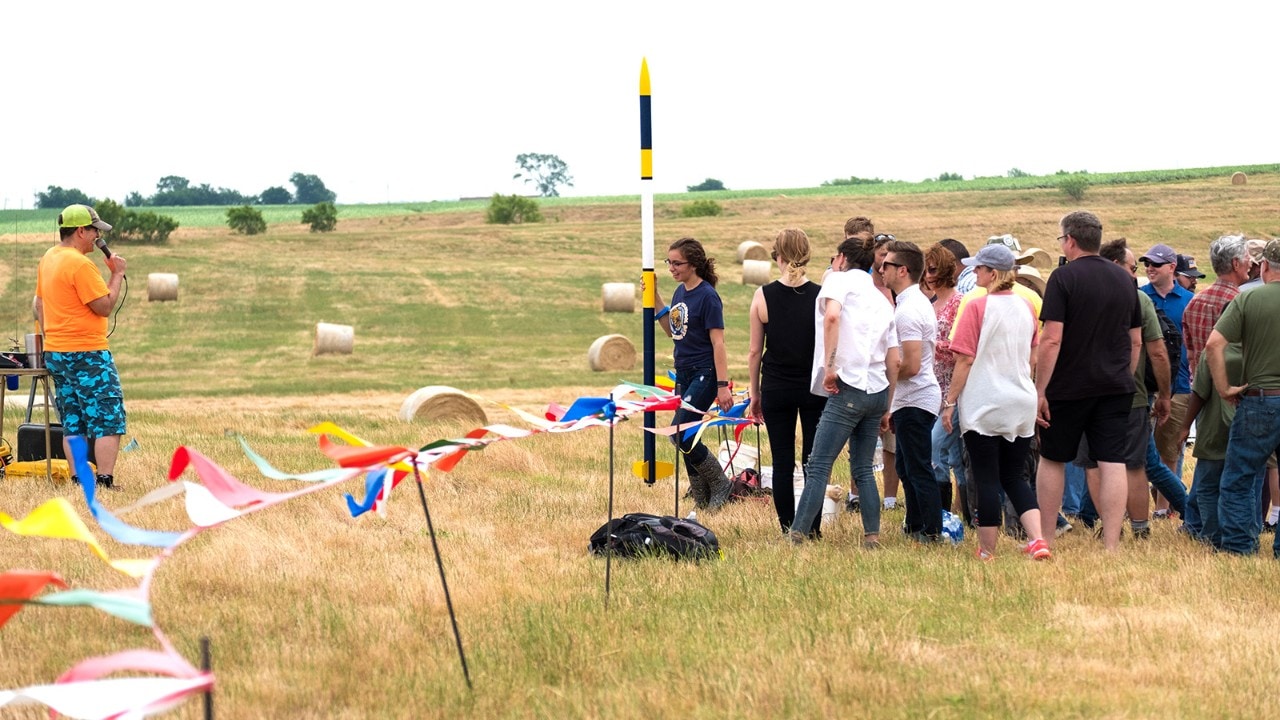 DARS members look on as Alex steps up to the launch pad with her model rocket. 