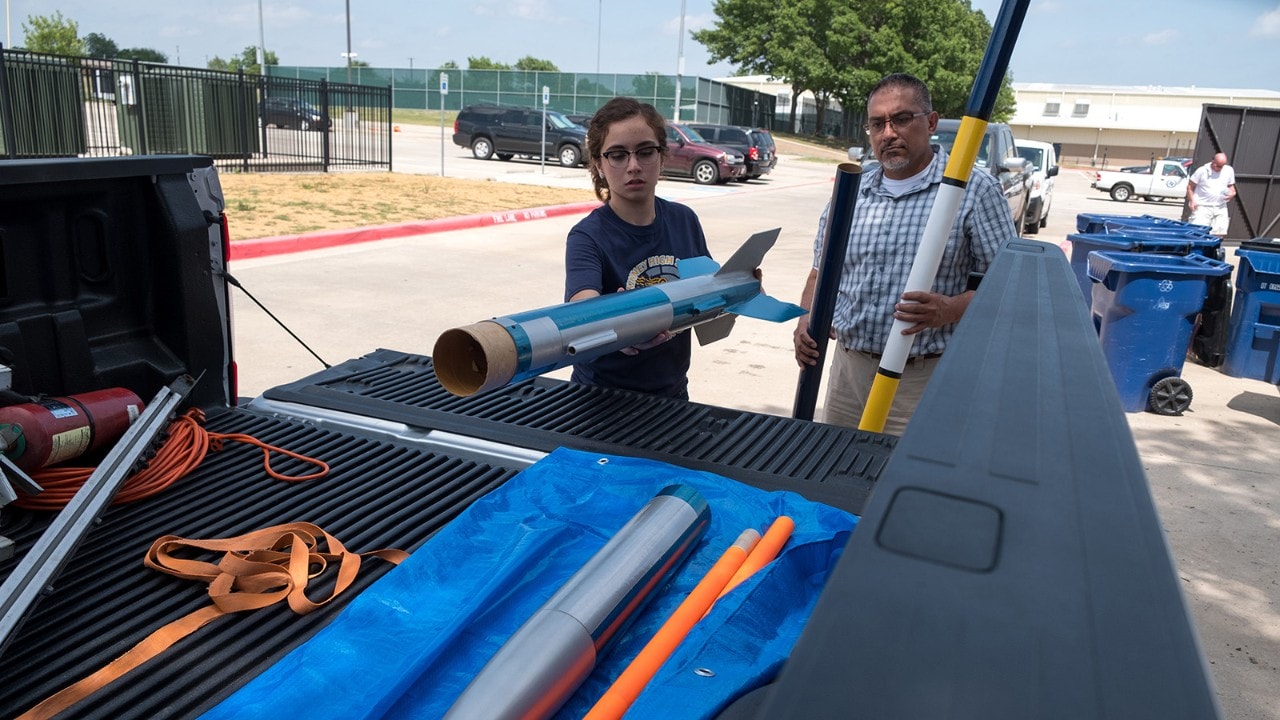 Alex and her dad load rockets into a pickup truck.
