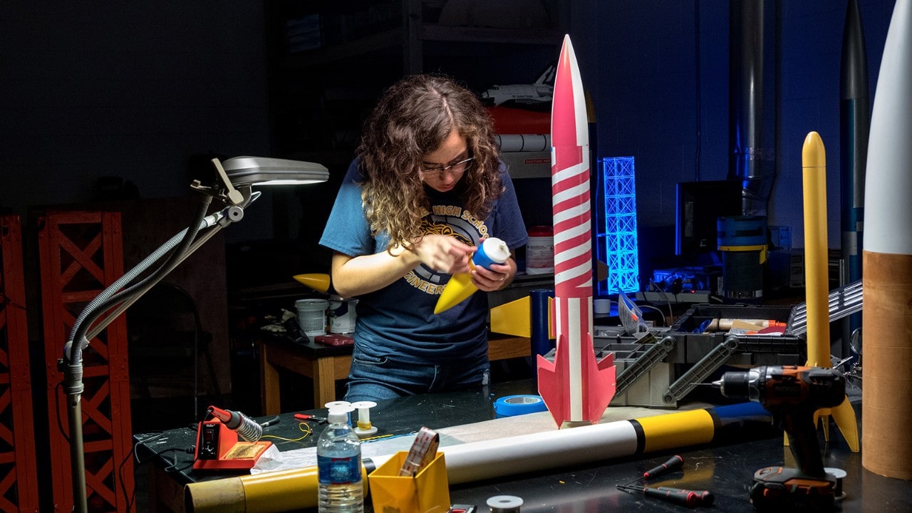 Alex assembles a rocket at her high school's lab.