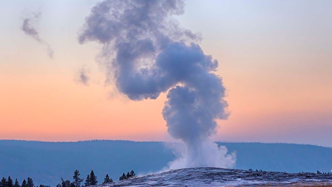 Old Faithful Geyser erupting at sunset, dusk. UNESCO World Heritage Site. Old Faithful Geyser, Upper Geyser Basin, Yellowstone National Park, Wyoming, USA.