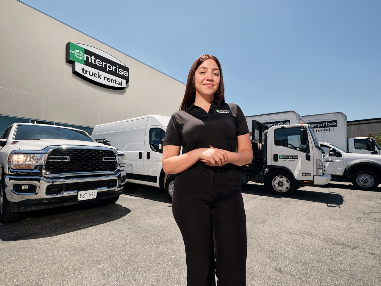 Enteprise woman smiling in front of a line of Enterprise trucks