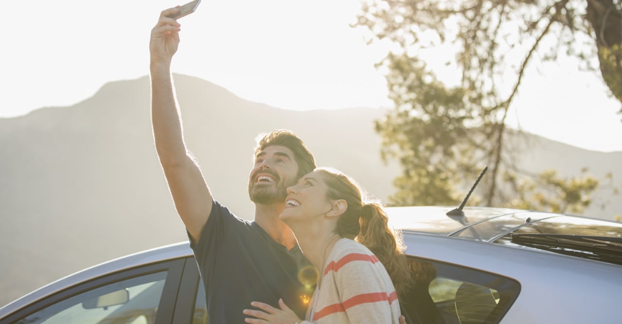 Pareja tomándose un selfi delante de un auto